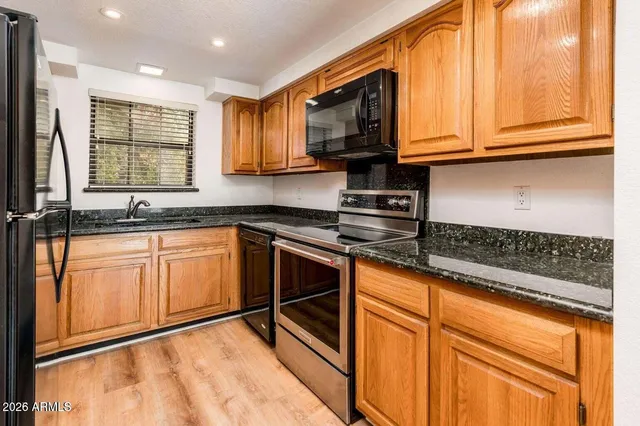 a kitchen with stainless steel appliances granite countertop a stove a sink and a microwave