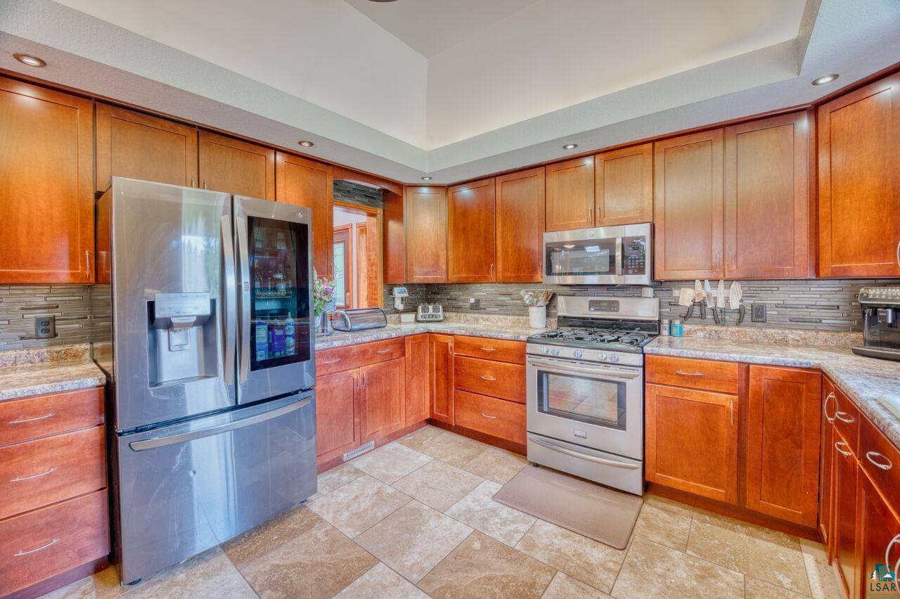 3935 Saari Road Hibbing, MN 55746 - Photo 9 of 48 Kitchen with stainless steel appliances, a tray ceiling, tasteful backsplash, and light tile floors