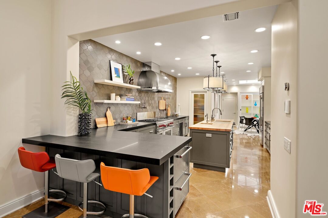 2305 Canyonback Road Los Angeles, CA 90049 - Photo 14 of 50 a kitchen with stainless steel appliances granite countertop a stove refrigerator a dining table and chairs with wooden floor