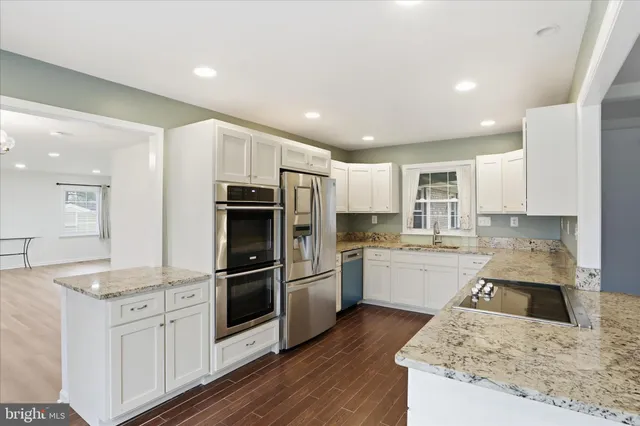 a kitchen with granite countertop white cabinets and stainless steel appliances