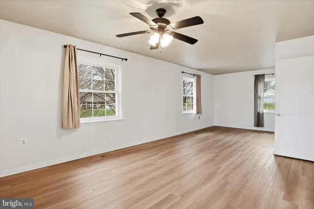 a view of an empty room with window and wooden floor