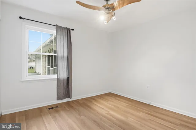 an empty room with a window and wooden floor