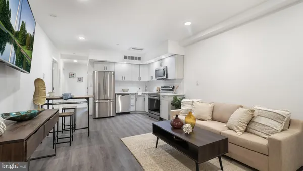a living room with stainless steel appliances furniture and a kitchen view