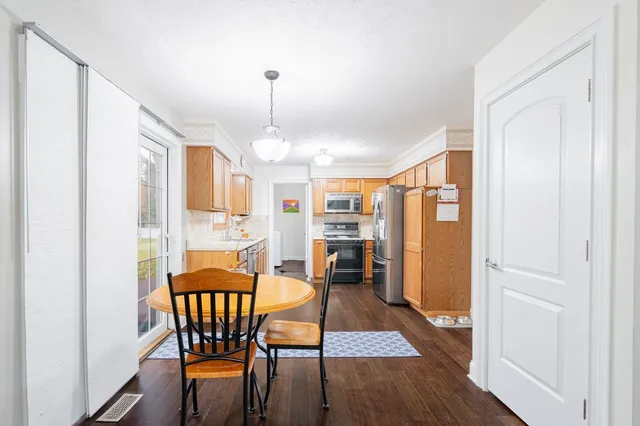 a kitchen with stainless steel appliances granite countertop a refrigerator a sink dishwasher a stove and white cabinets with wooden floor