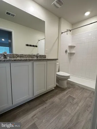 a bathroom with a granite countertop sink a toilet and a mirror
