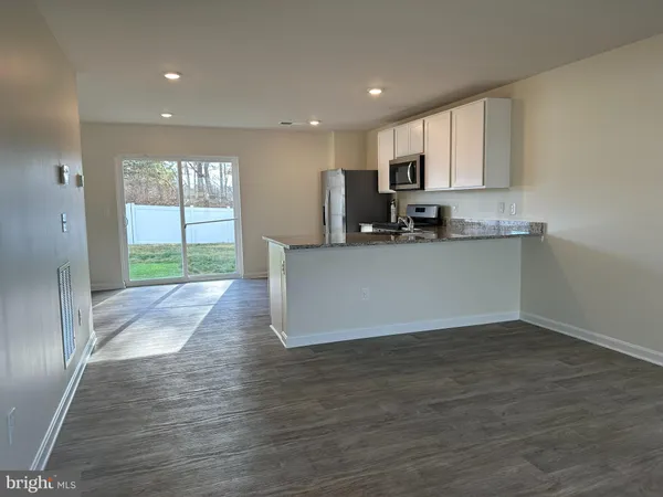a view of a kitchen with kitchen island a sink wooden floor and a refrigerator