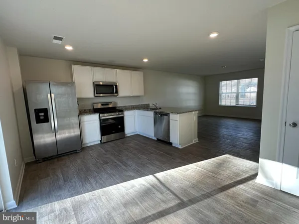 a kitchen with granite countertop a refrigerator and a stove top oven
