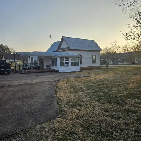 a view of a big house with a big yard and large trees