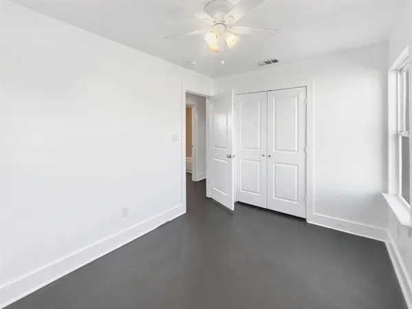 an empty room with a fan & a ceiling fan