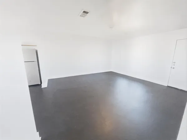 an empty room with wooden floor and fan