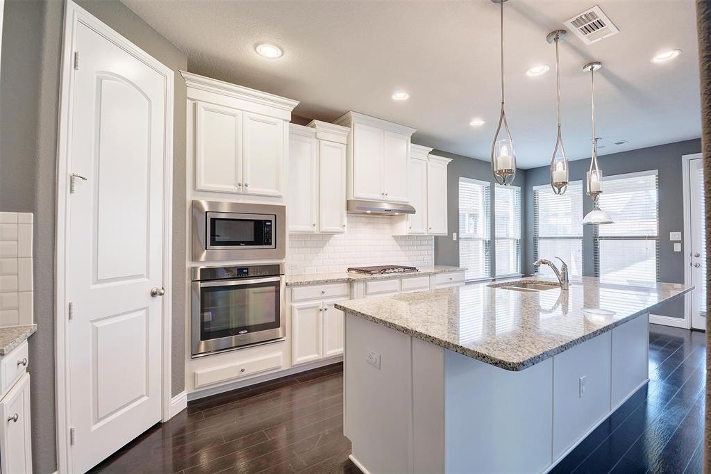 a large kitchen with granite countertop a sink a counter top space stainless steel appliances and cabinets