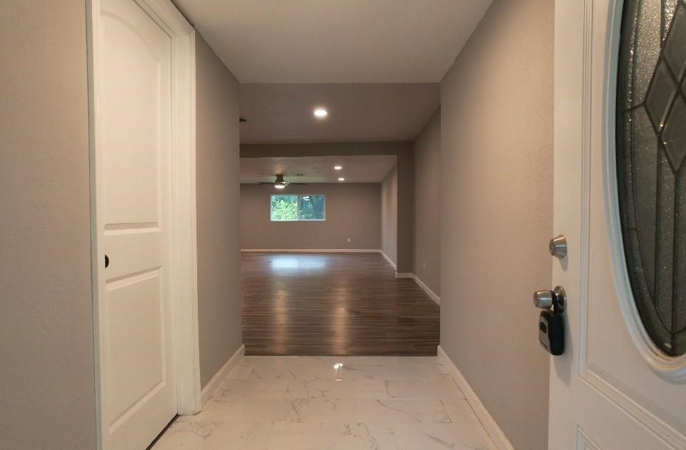 25373 Goodson Road Splendora, TX 77372 - Photo 33 of 43 Inviting hallway with a stylish door, elegant wood flooring, and detailed molding. The warm design makes it a charming entry point, ideal for showcasing the property's potential for remodel or flip opportunities.