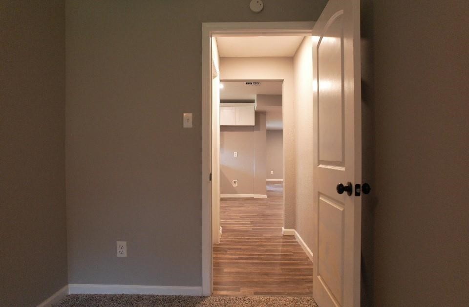 25373 Goodson Road Splendora, TX 77372 - Photo 40 of 43 Spacious hallway with an open door, featuring elegant wall finishes, hardwood flooring, and modern details like molding and door handles. A well-lit space that enhances the property’s overall appeal.