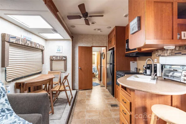 a dining room with stainless steel appliances granite countertop a couch a dining table and chairs with wooden floor