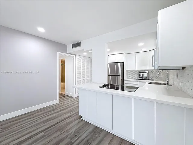 a kitchen with white cabinets sink and refrigerator