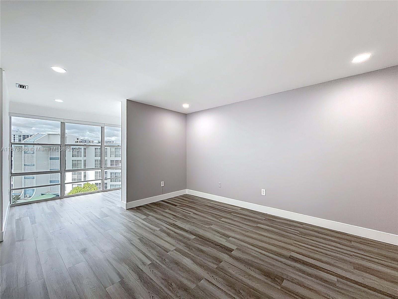 17620 Atlantic Boulevard, Unit 505 Sunny Isles Beach, FL 33160 - Photo 18 of 35 a view of an empty room with wooden floor and a window