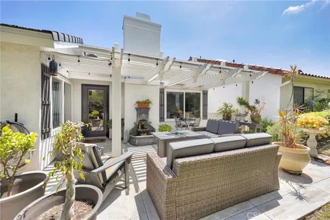 a view of a patio with couches chairs potted plants and floor to ceiling window and potted plants