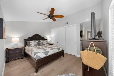a bedroom with a bed a dresser and potted plants with wooden floor