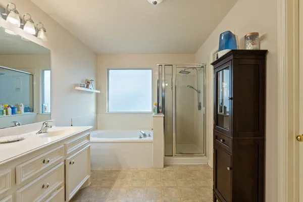 a bathroom with a double vanity sink a mirror a bathtub and shower