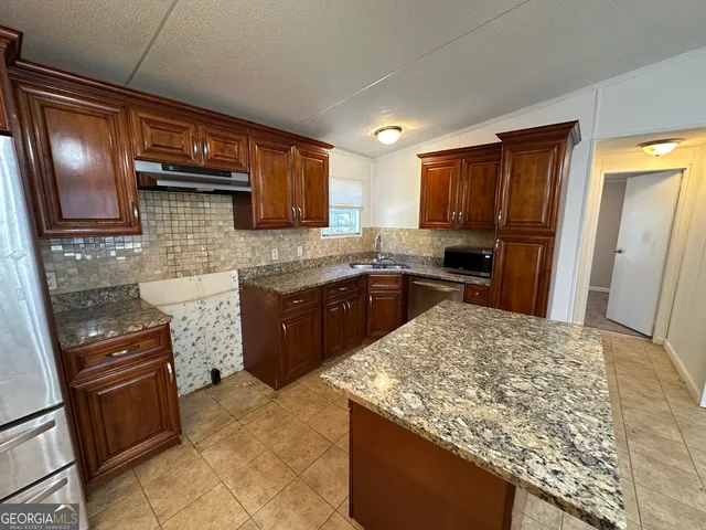 a kitchen with kitchen island granite countertop wooden cabinets and a sink