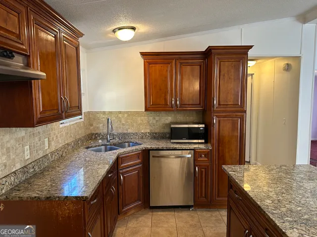a kitchen with stainless steel appliances granite countertop wooden cabinets a sink and dishwasher