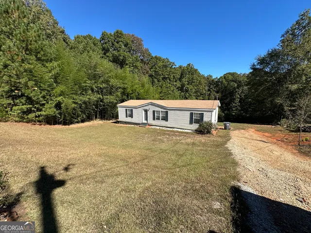 a yellow house with tall trees in the background