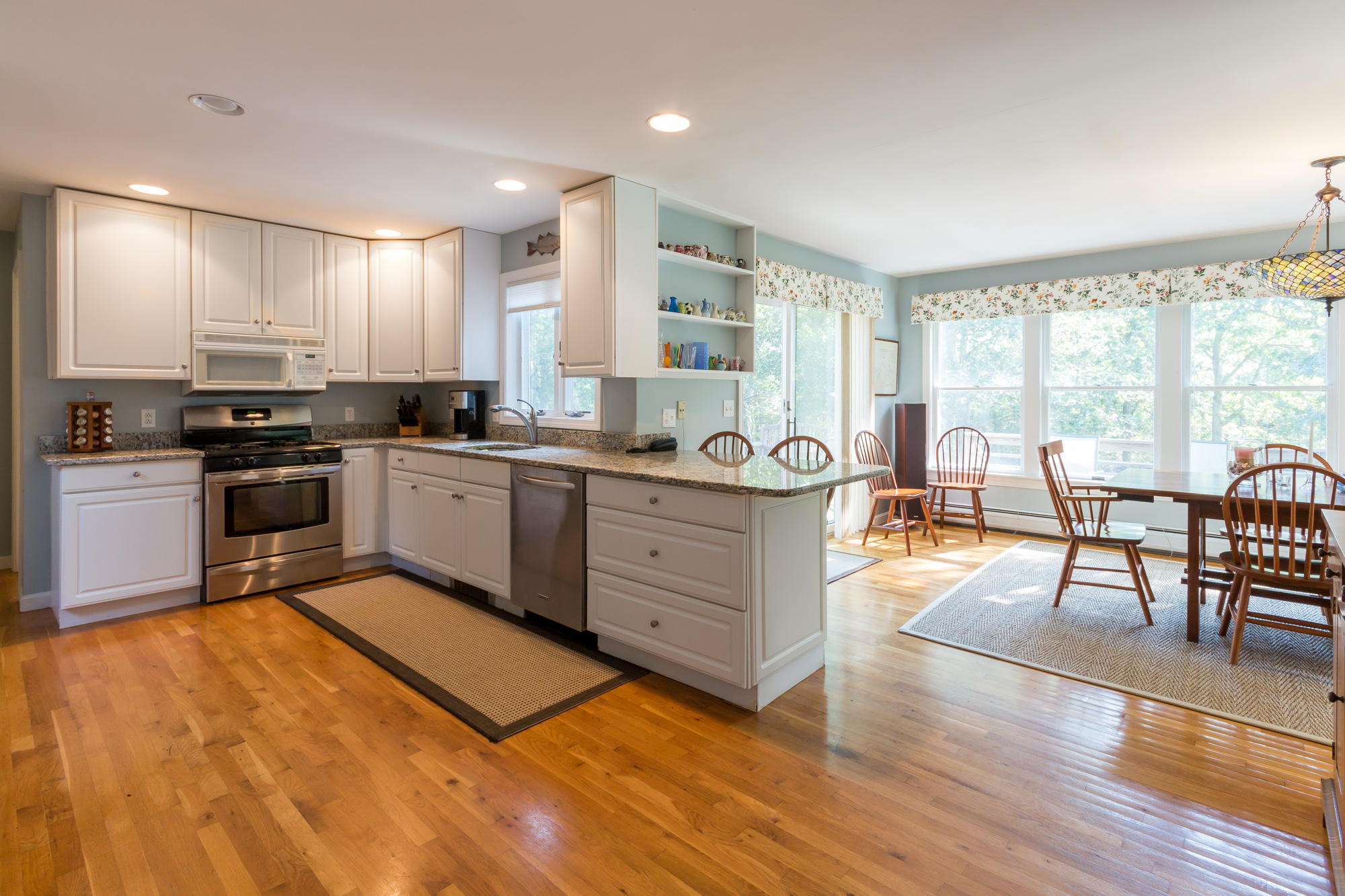 321 Chappaquiddick Road Edgartown, MA 02539 - Photo 6 of 35 a kitchen with stainless steel appliances granite countertop a stove top oven a sink dishwasher a dining table and chairs with wooden floor