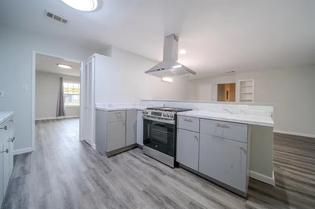 a open kitchen with a white stove cabinets and wooden floor