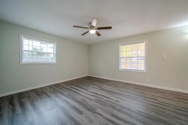 a view of an empty room with wooden floor and a window