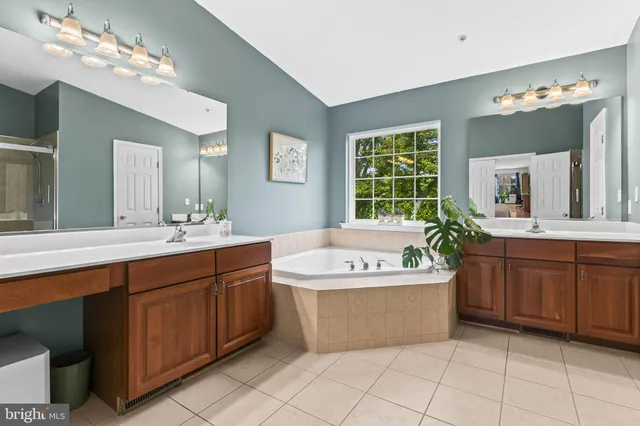 a spacious bathroom with a tub a sink double vanity and a mirror