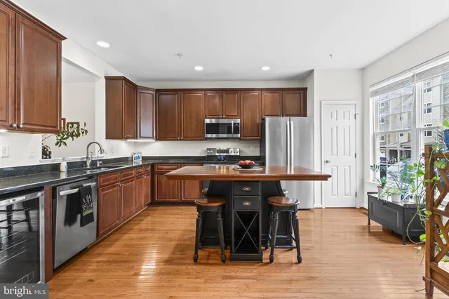 a kitchen with stainless steel appliances granite countertop a table chairs sink refrigerator and cabinets
