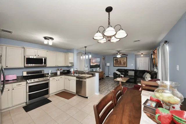 a kitchen with stainless steel appliances granite countertop a stove top oven a sink a stove a dining table and chairs with wooden floor