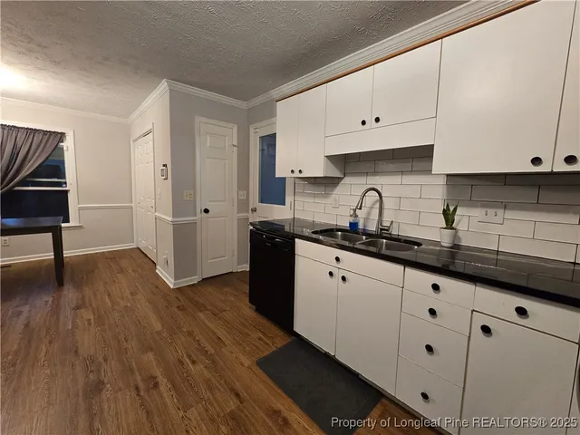 a kitchen with granite countertop white cabinets and wooden floor