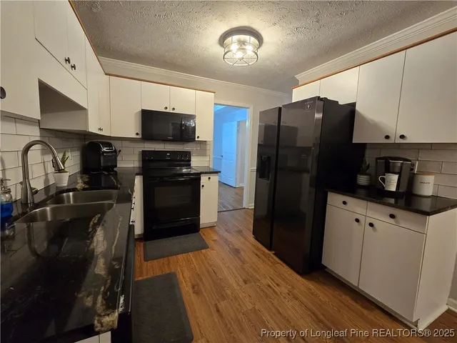a kitchen with granite countertop a refrigerator and a stove top oven