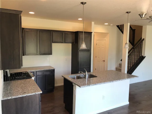 a kitchen with kitchen island granite countertop a sink a counter and stainless steel appliances