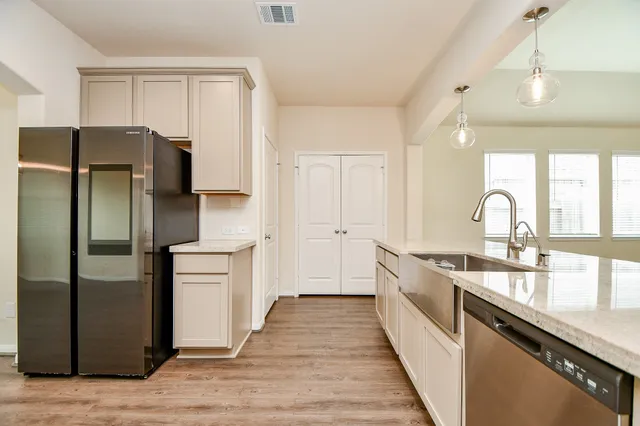 a kitchen with stainless steel appliances granite countertop a sink dishwasher a stove and a microwave oven with wooden floor