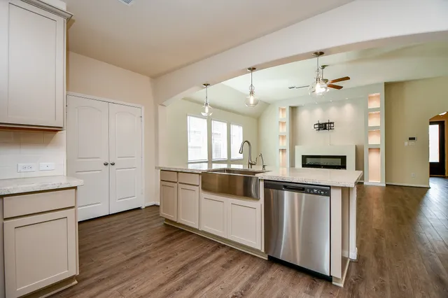 a view of a room with wooden floor a ceiling fan and windows
