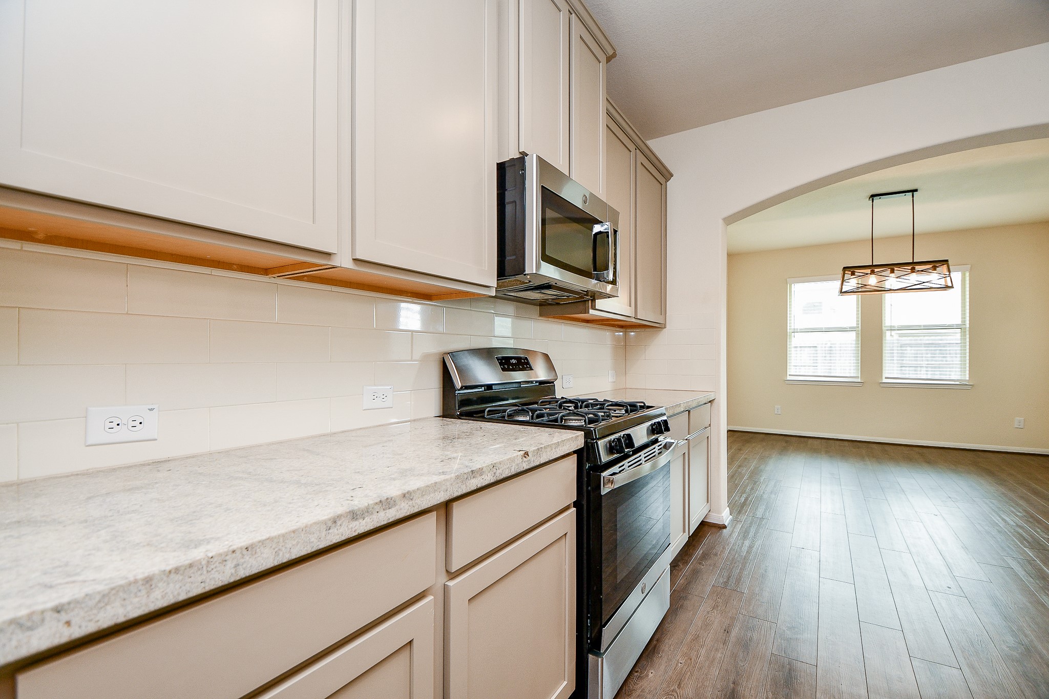 15210 Ordie Run Drive Humble, TX 77346 - Photo 15 of 40 a kitchen with stainless steel appliances granite countertop a sink dishwasher a stove and a microwave oven with wooden floor