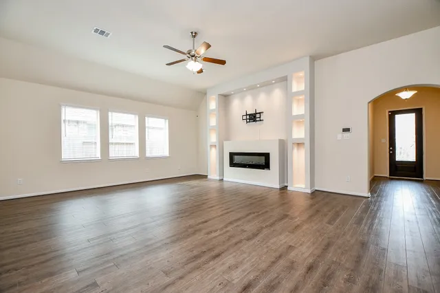 a view of an empty room with wooden floor and a fireplace