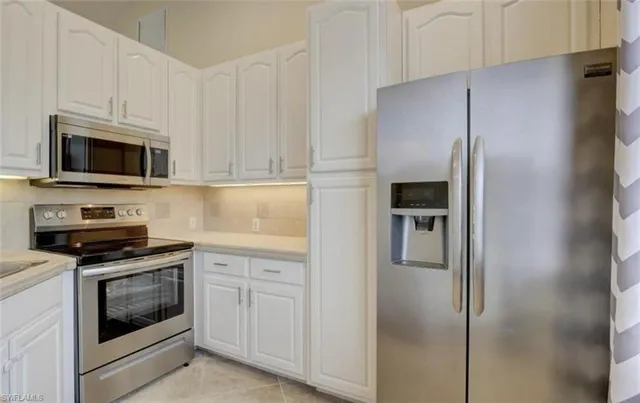 a kitchen with stainless steel appliances white cabinets and a refrigerator