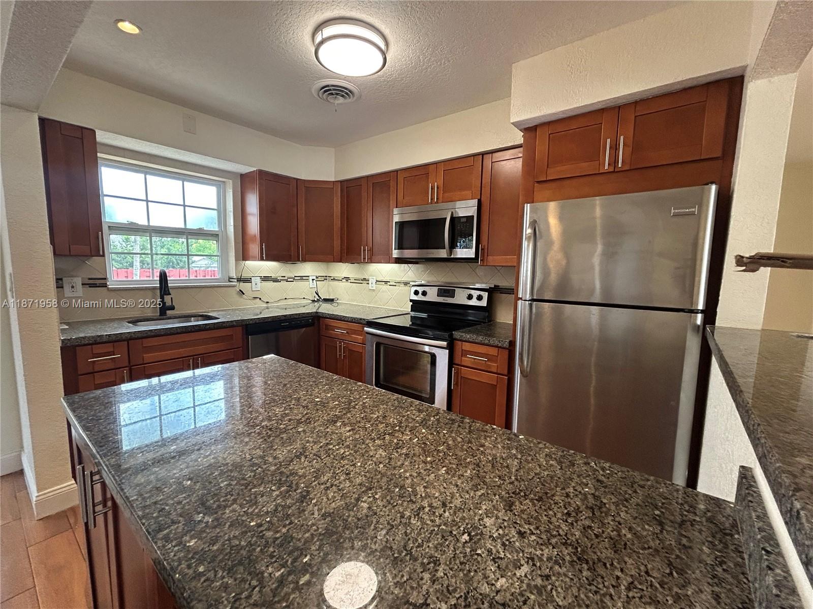 3219 Wilson Street Hollywood, FL 33021 - Photo 5 of 15 a kitchen with stainless steel appliances granite countertop a stove a sink dishwasher a refrigerator and a microwave