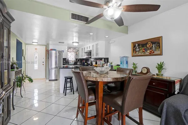 a dining area with stainless steel appliances kitchen island granite countertop a dining table chairs and a refrigerator