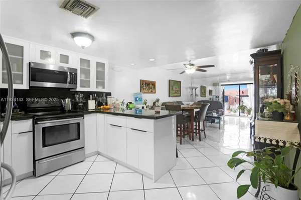 a kitchen with stainless steel appliances granite countertop a stove top oven a sink a dining table and chairs with white cabinets