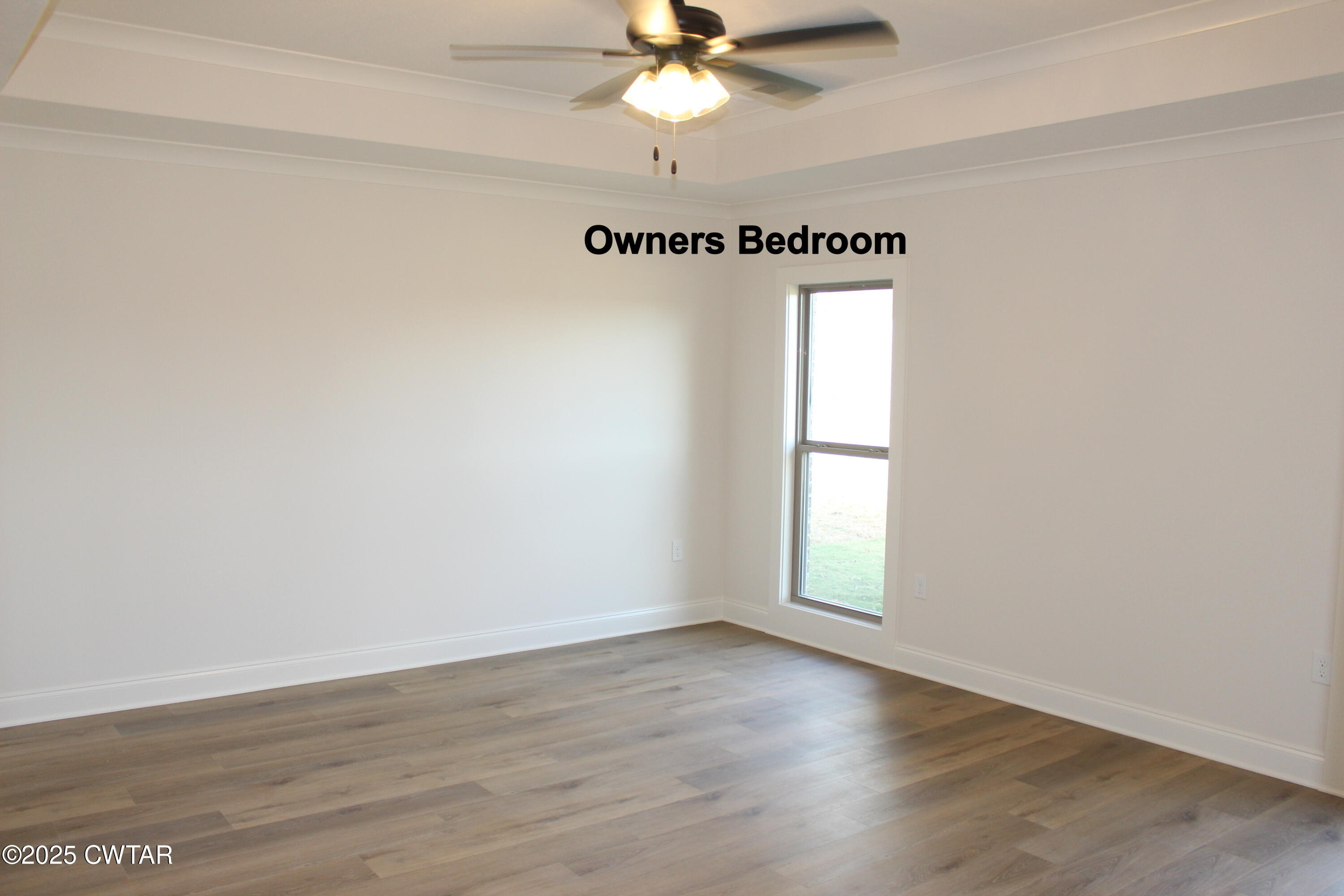 57 Brompton Cove Jackson, TN 38305 - Photo 6 of 15 an empty room with wooden floor fan and windows