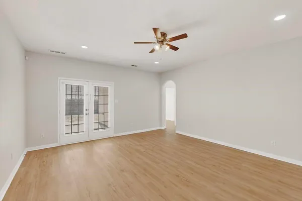 an empty room with wooden floor fan and windows