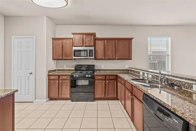 a kitchen with stainless steel appliances granite countertop a stove a sink and a microwave