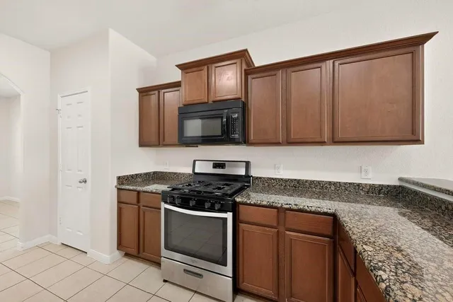 a kitchen with granite countertop white cabinets stainless steel appliances and a sink