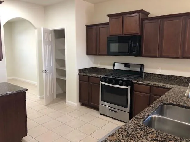 a kitchen with stainless steel appliances granite countertop a stove a microwave and a sink