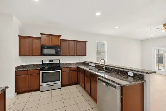 a kitchen with stainless steel appliances granite countertop a sink stove top oven and microwave