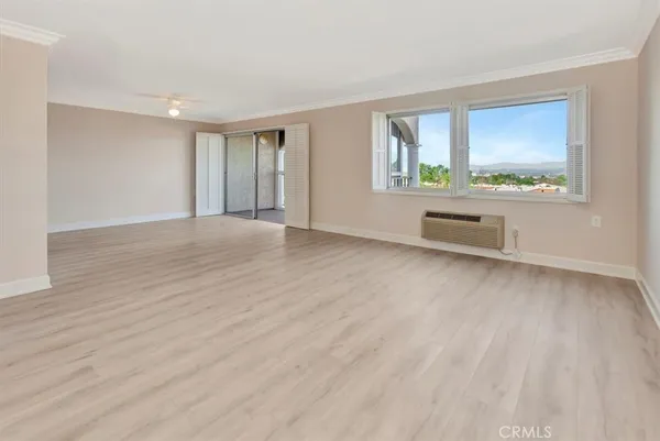a view of an empty room with wooden floor and a window